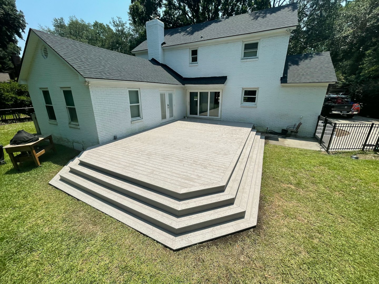 A new composite deck with tiered steps leading to a lawn.