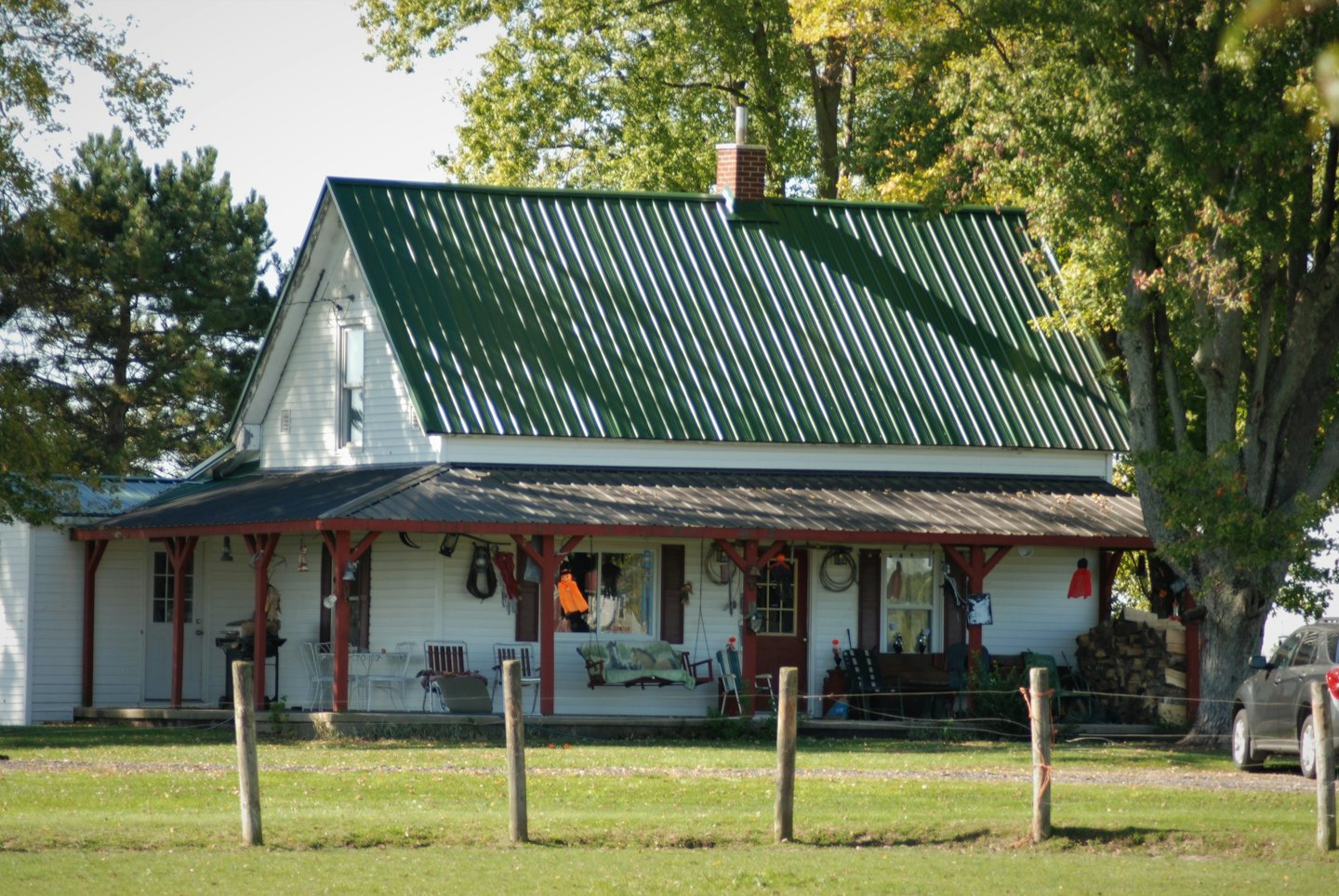 White clapboard house with green roof and red porch columns.