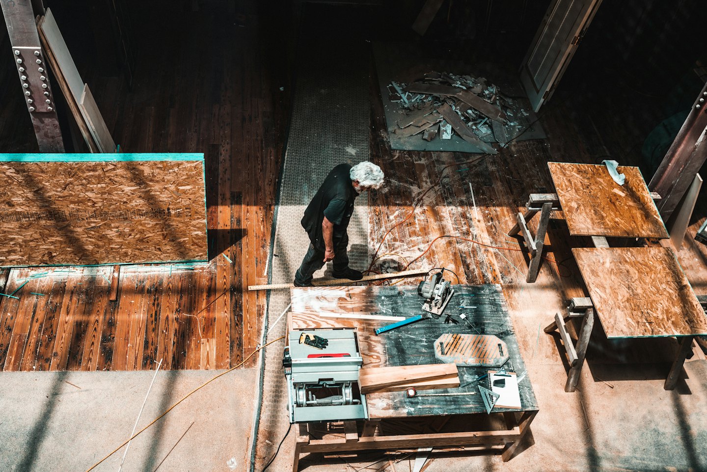 Contractor works on renovation with tools and wood inside a room.