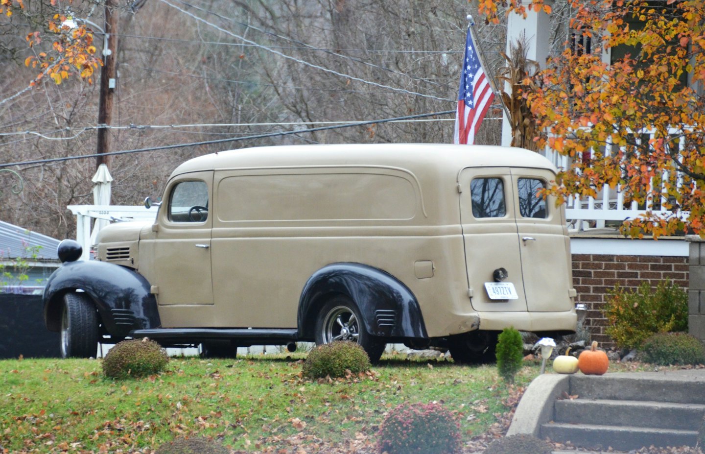 Vintage tan van parked on a grassy hill near a house.